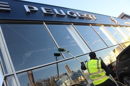 Man cleans large car showroom windows